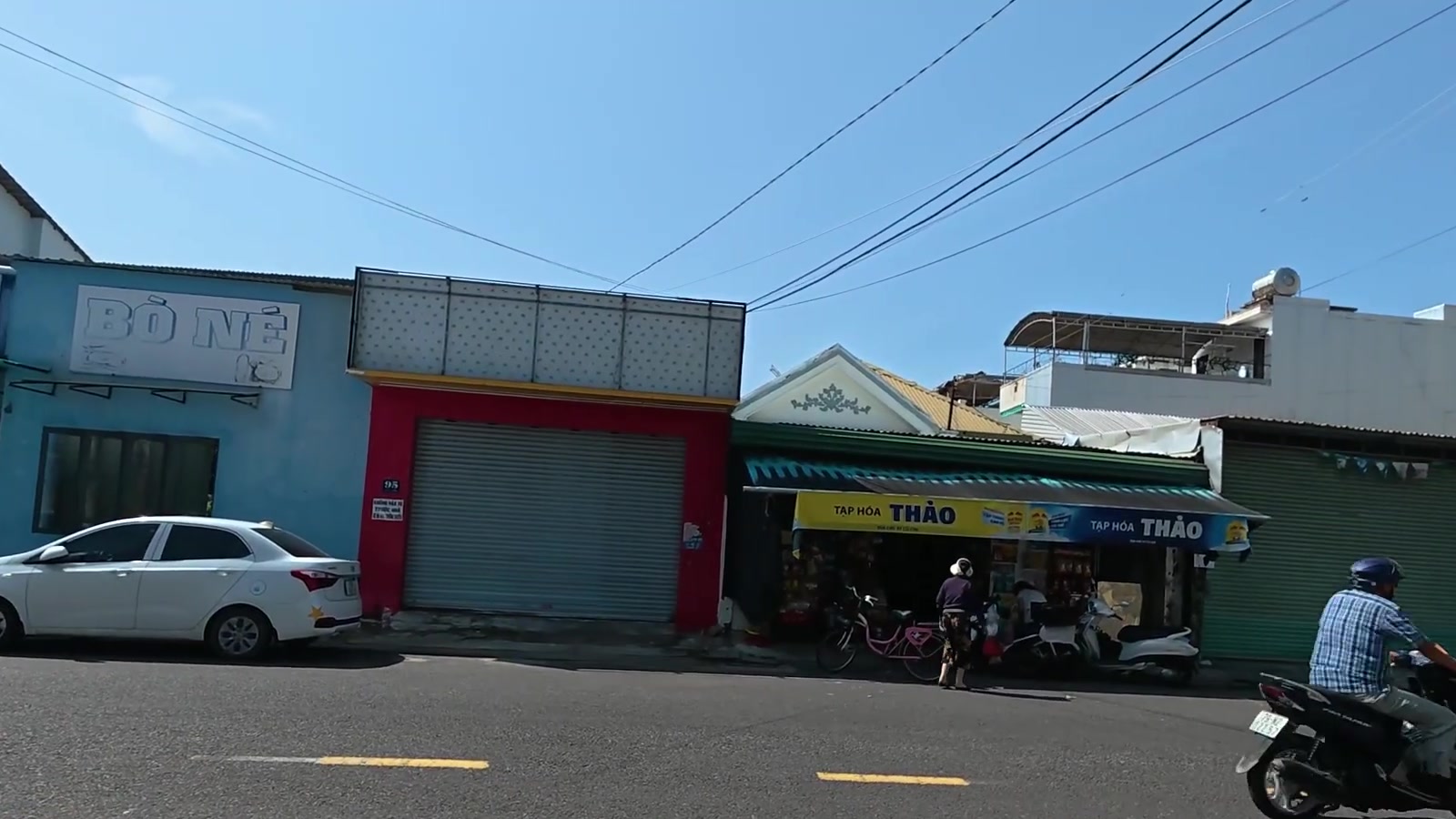 Mặt tiền lô đất số 95 đường Củ Chi khu Vĩnh Hải Nha Trang, công trình cũ mặt đỏ cửa cuốn, hai bên là quán ăn và tạp hóa