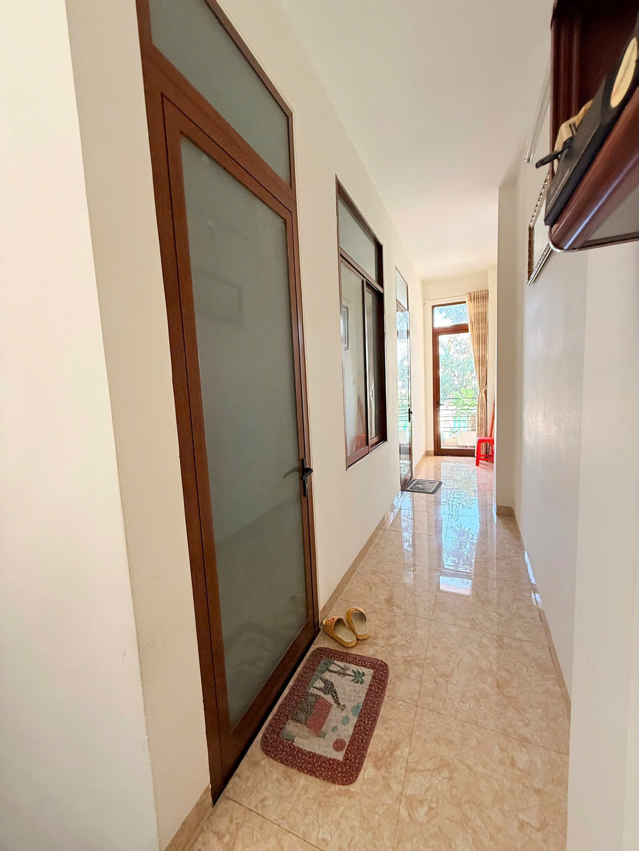 Hành lang tầng trên nhà Diệp Minh Tuyền Nha Trang, cửa kính khung gỗ, cuối hành lang là cửa ra ban công