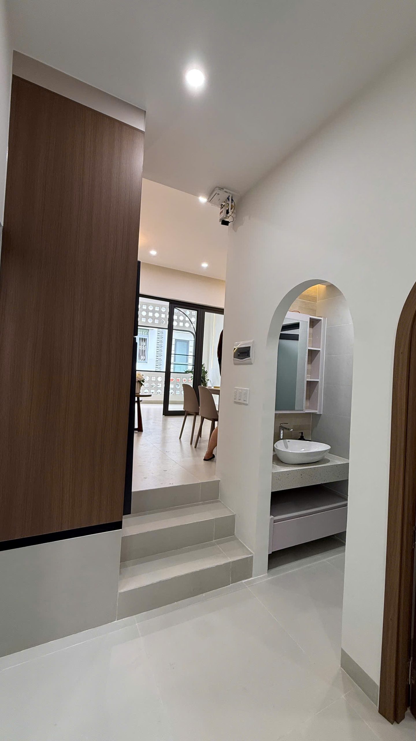 Khu vệ sinh nhà Ngô Đến, lavabo và kệ gương đặt trong hốc tường bo vòm, cạnh bậc thềm lên khu phòng khách