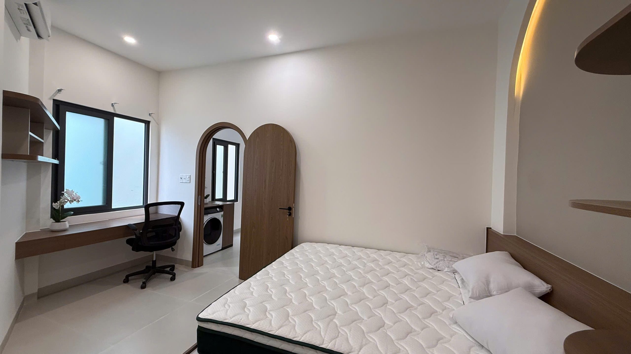 Phòng ngủ nhà Ngô Đến với bàn làm việc dọc cửa sổ, ghế xoay và cửa vòm thông sang khu giặt