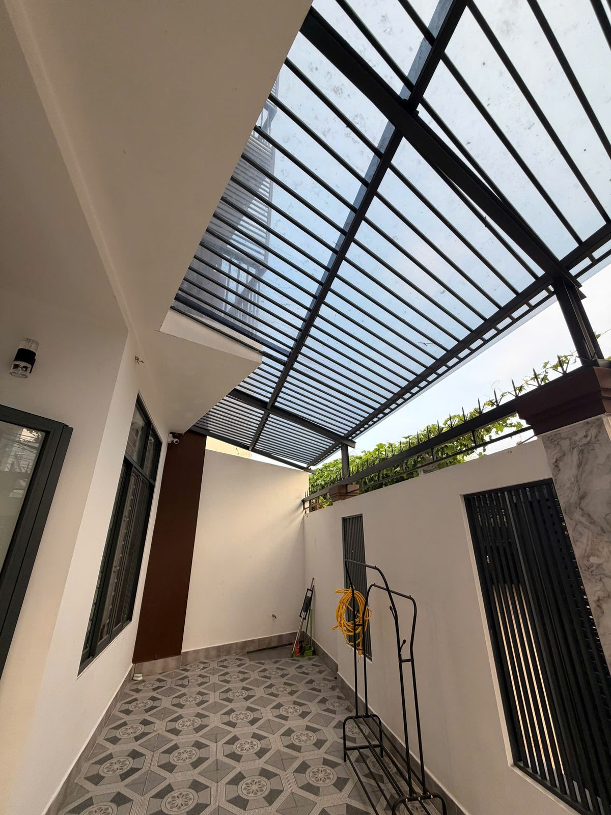 Khoảng giếng trời bên hông nhà Vĩnh Điềm lợp mái lấy sáng khung sắt, nền lát gạch hoa văn, có giàn cây leo trên tường